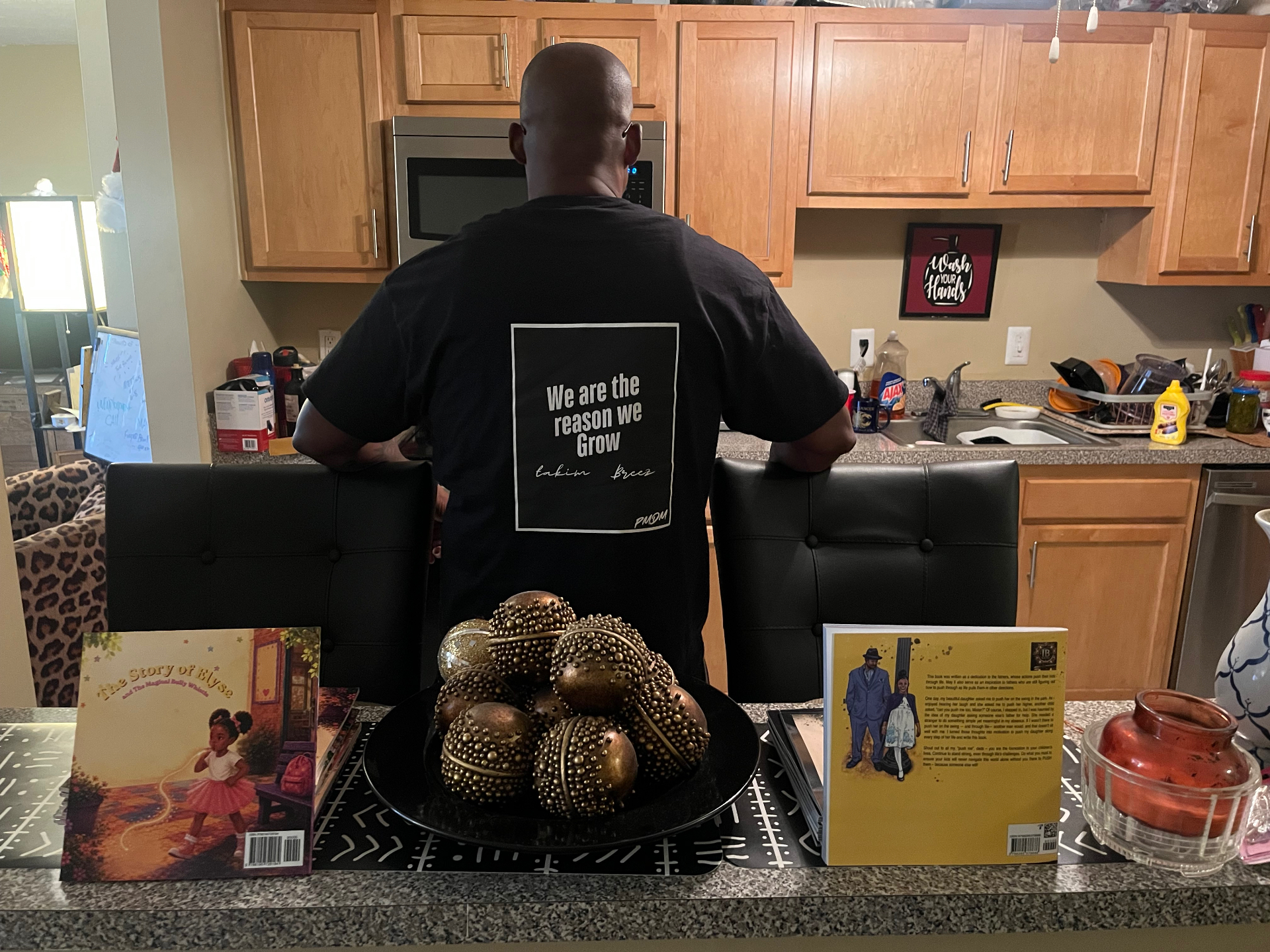IB Writes wearing the Push Me Dad Movement t-shirt, with books on the counter